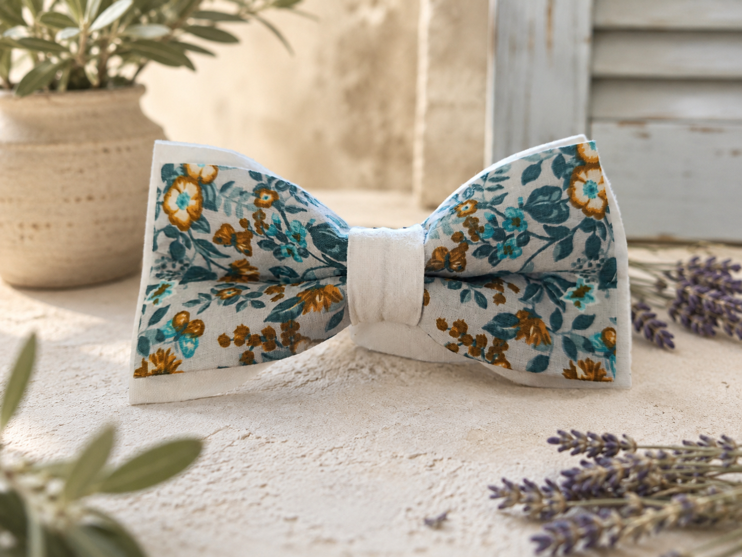 Nœud papillon Liberty Marcel Fleur Bleue en coton, motifs floraux bleu et ocre sur tissu écru upcyclé, présenté dans un décor provençal.