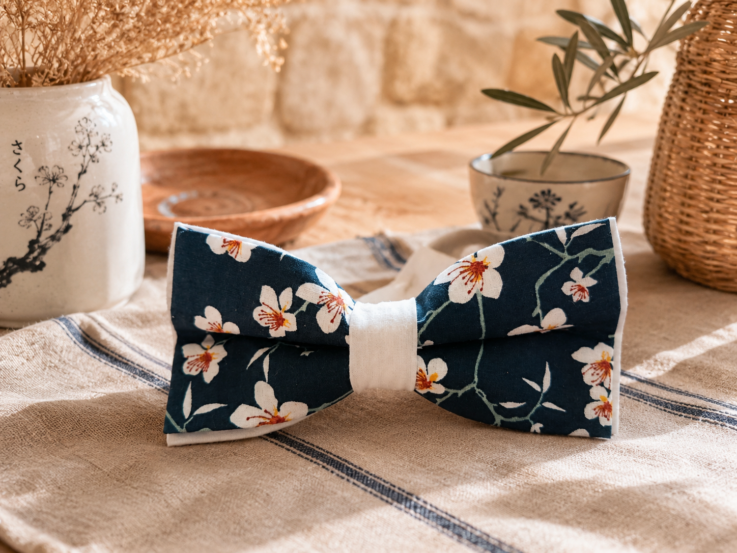 Nœud papillon artisanal à motif sakura mis en scène dans une décoration inspirée du Japon traditionnel.